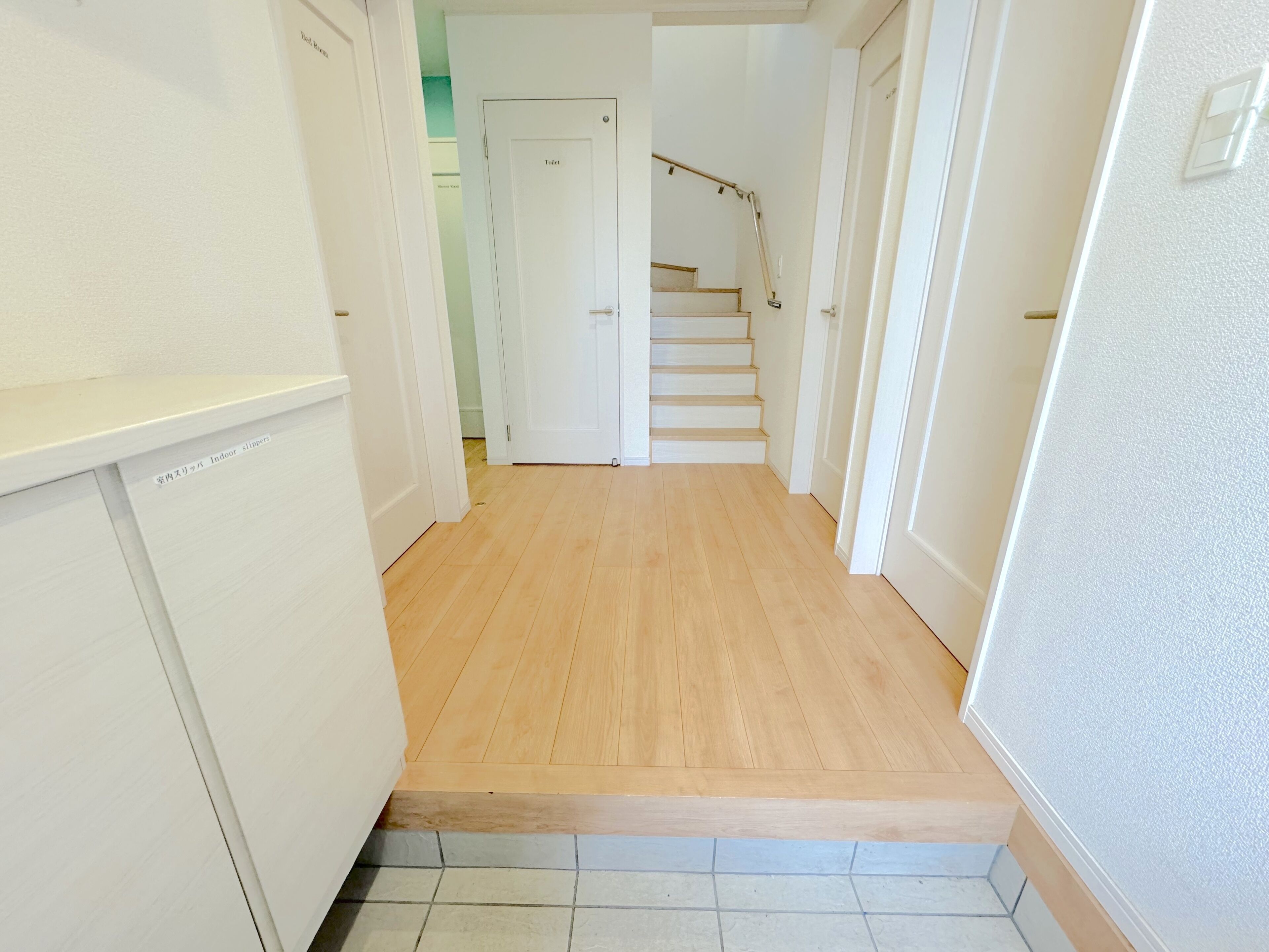 A narrow hallway with a wooden floor leading to a staircase.