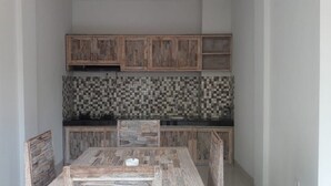 A compact kitchen with wooden cabinets, a tiled backsplash, and a central island. - Villa Uma Dangin (Ubud)