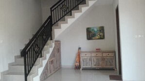 A staircase with a black railing, a wooden cabinet with drawers, and a painting on the wall. - Villa Uma Dangin (Ubud)