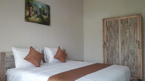 A bedroom with a large bed, two pillows, a wooden wardrobe, and a painting on the wall. - Villa Uma Dangin (Ubud)