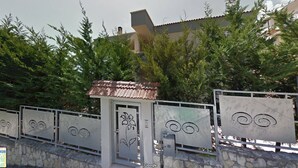 A gated entrance with decorative metal panels, a small tiled-roofed structure, and a stone wall. - B&B Pizzomunno e Cristalda Rooms (Vieste)