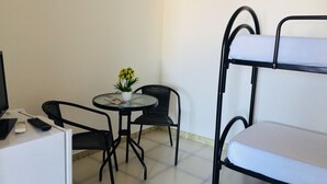 A room with a bunk bed, a small round table with chairs, a potted plant, and a television. - B&B Pizzomunno e Cristalda Rooms (Vieste)