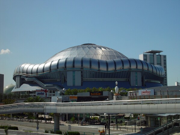 Un stade moderne doté d’une structure en forme de dôme unique, entouré d’infrastructures urbaines.