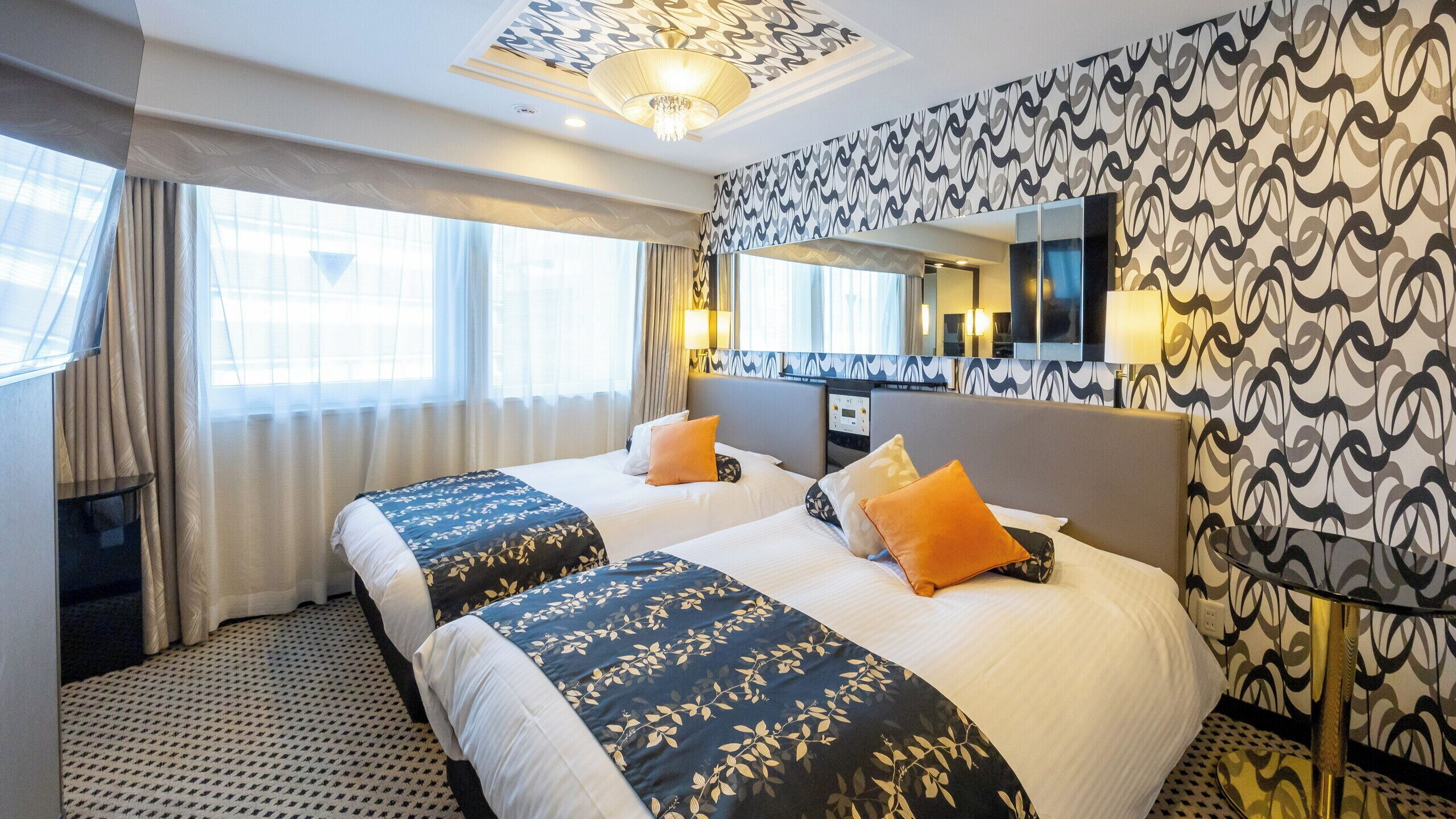 A hotel room with two beds, a large mirror, and a patterned wall.