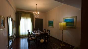 A dining room with a chandelier, dining table, chairs, and a lamp.