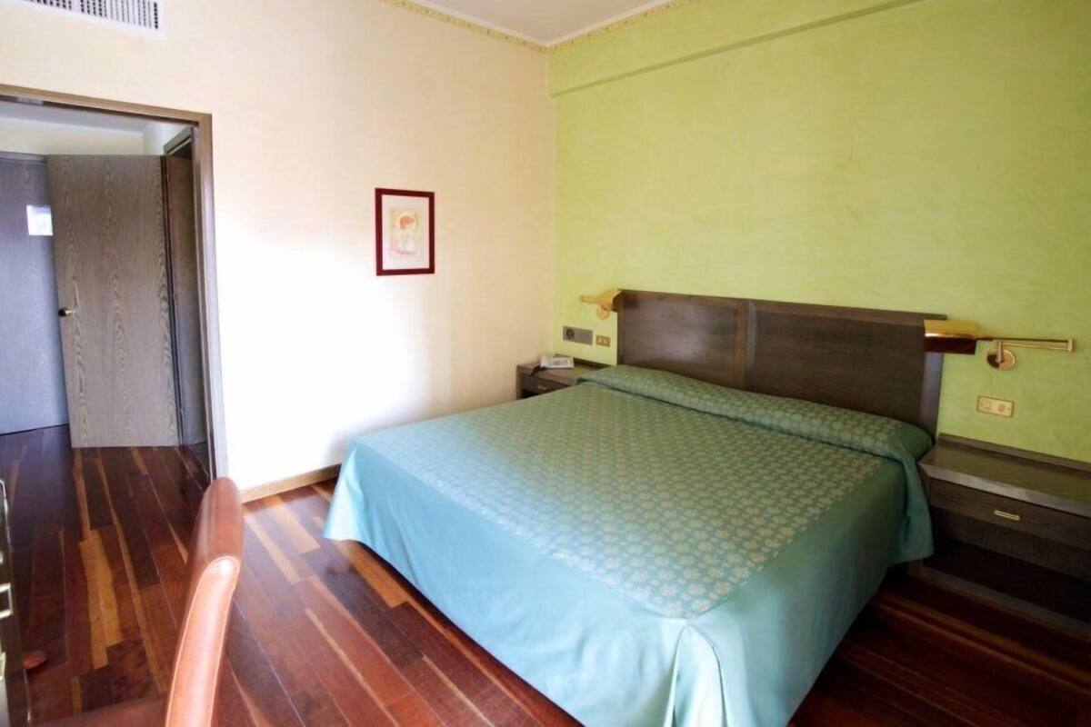 Ein Schlafzimmer mit einem Bett, einem Nachttisch, einer Kommode und einer Tür zu einem weiteren Raum.