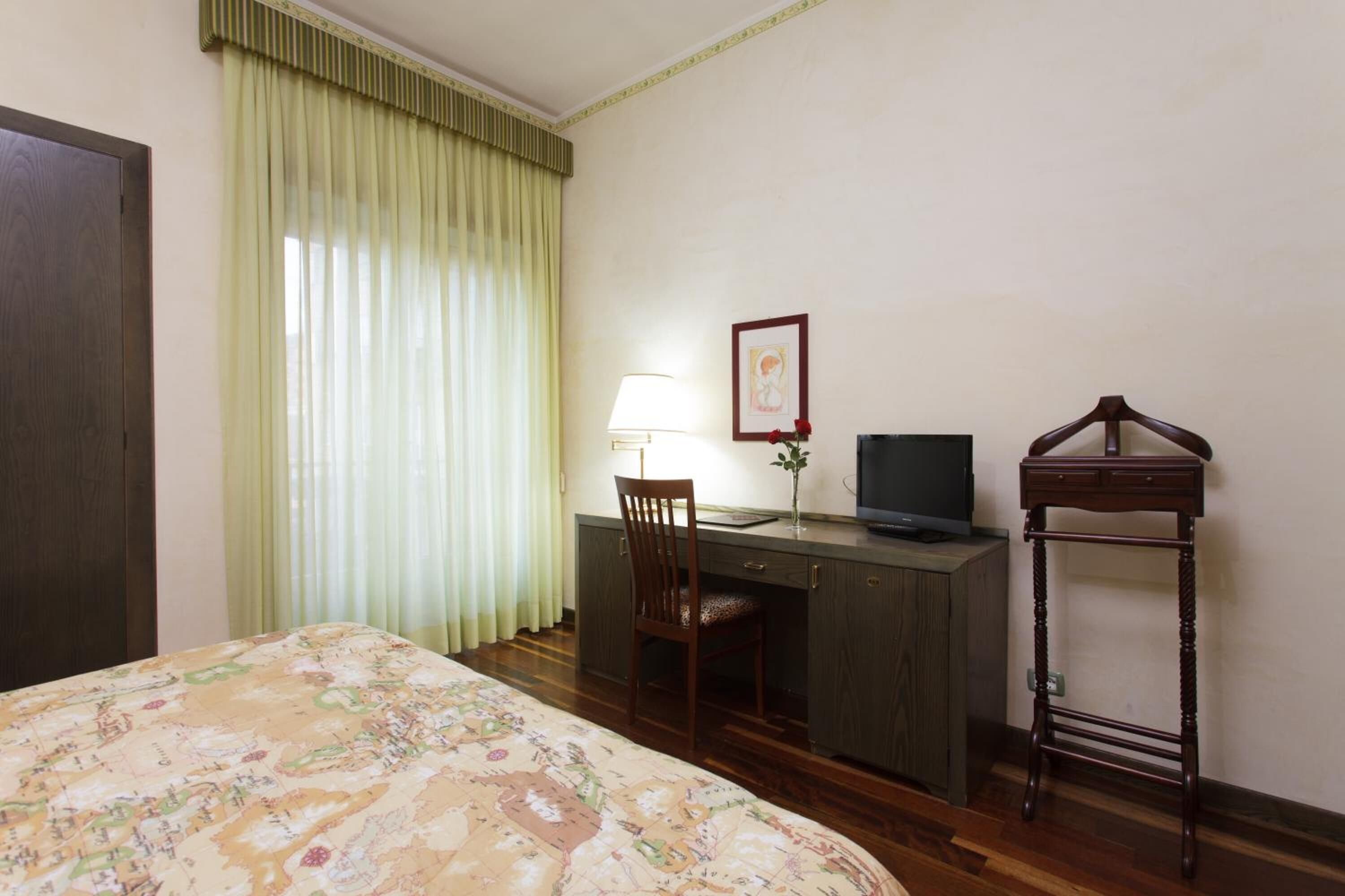 Una habitación de hotel con una cama, un escritorio con una silla, un televisor y una mesita.