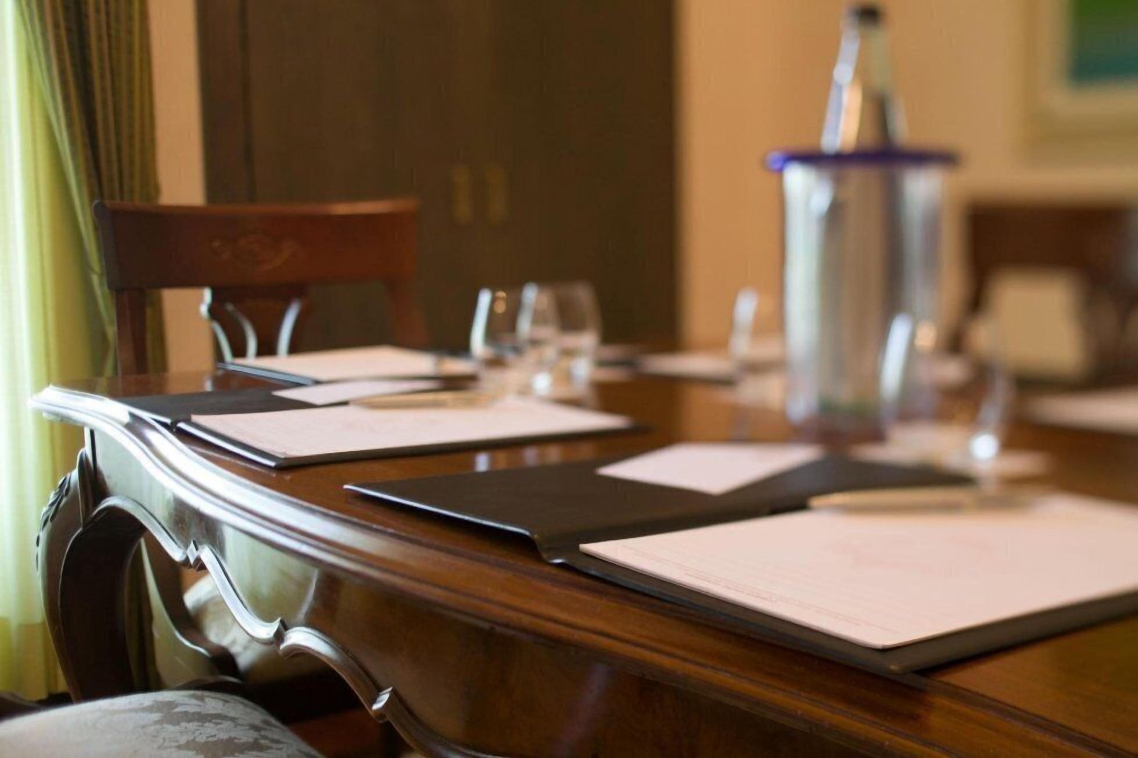 A conference table with documents, a water bottle, and glasses.
