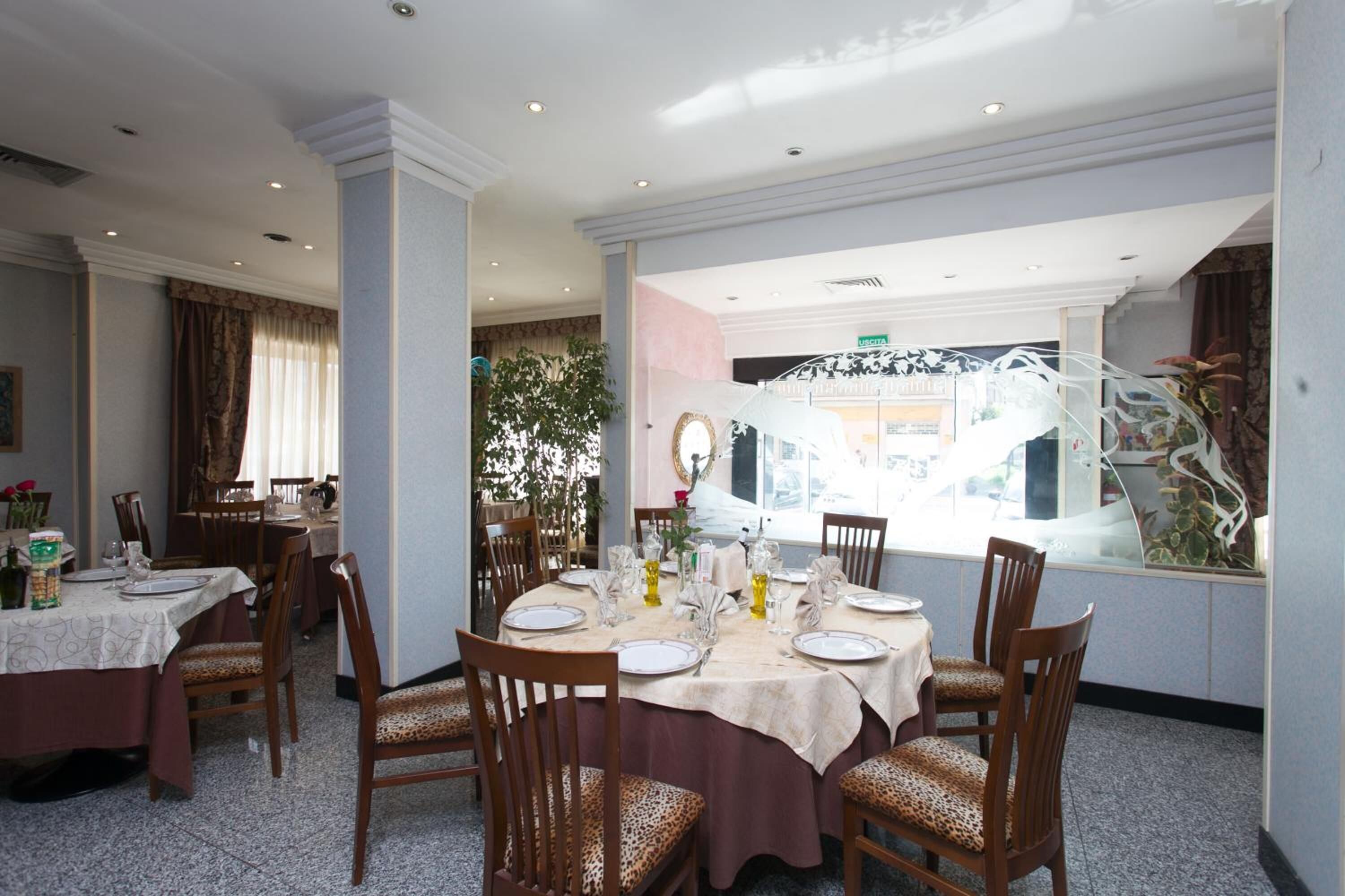 A dining area with round tables, chairs, and a large window with a view of the outside.