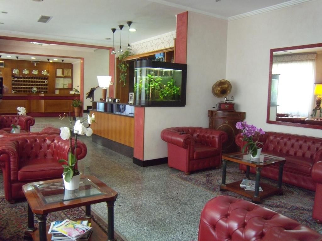 A lobby with red leather sofas, a reception desk, a fish tank, and a mirror.