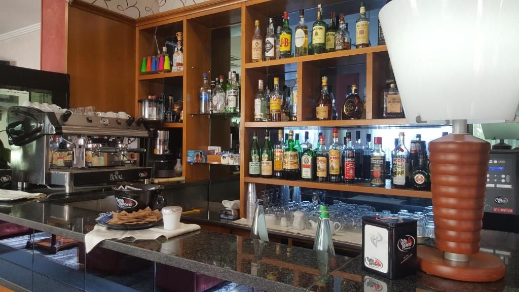 Een bar met planken vol verschillende drankflessen, een koffieapparaat en enkele glazen op de toonbank.