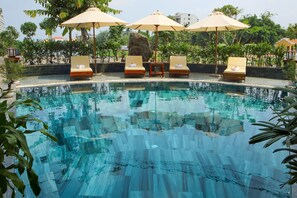 Una piscina al aire libre, sombrillas, sillones reclinables de piscina