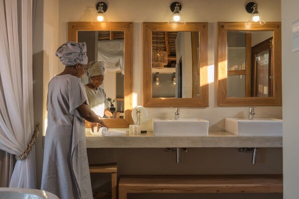 Un baño con dos lavamanos, armarios de madera y un espejo con marco de madera.