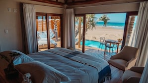 Un dormitorio con una cama grande, vistas a la playa y una zona de piscina.