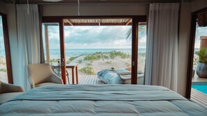 Un dormitorio con una cama grande, vista a la playa y una piscina.