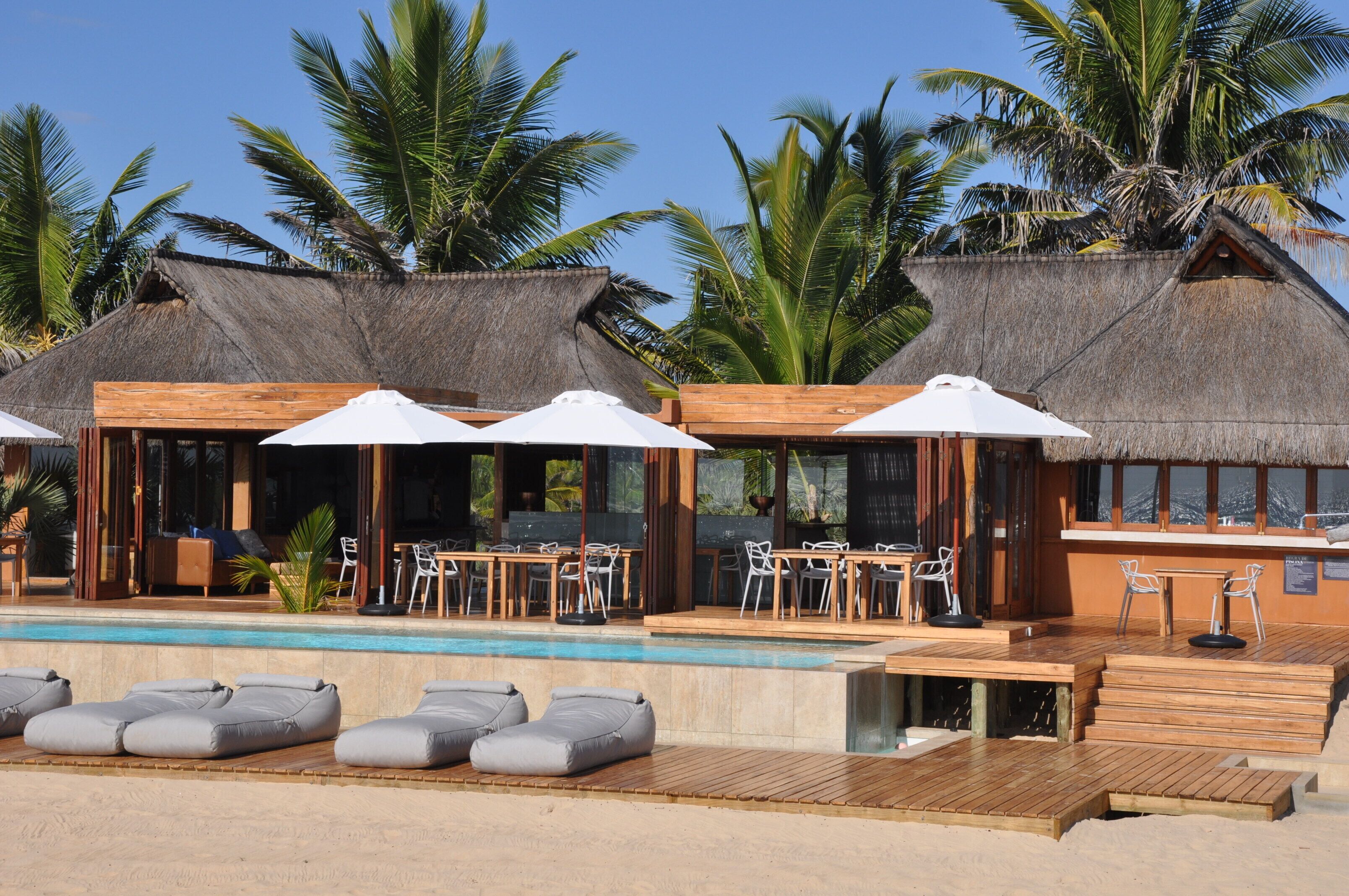 A resort with thatched-roof villas, a pool, and outdoor seating areas.