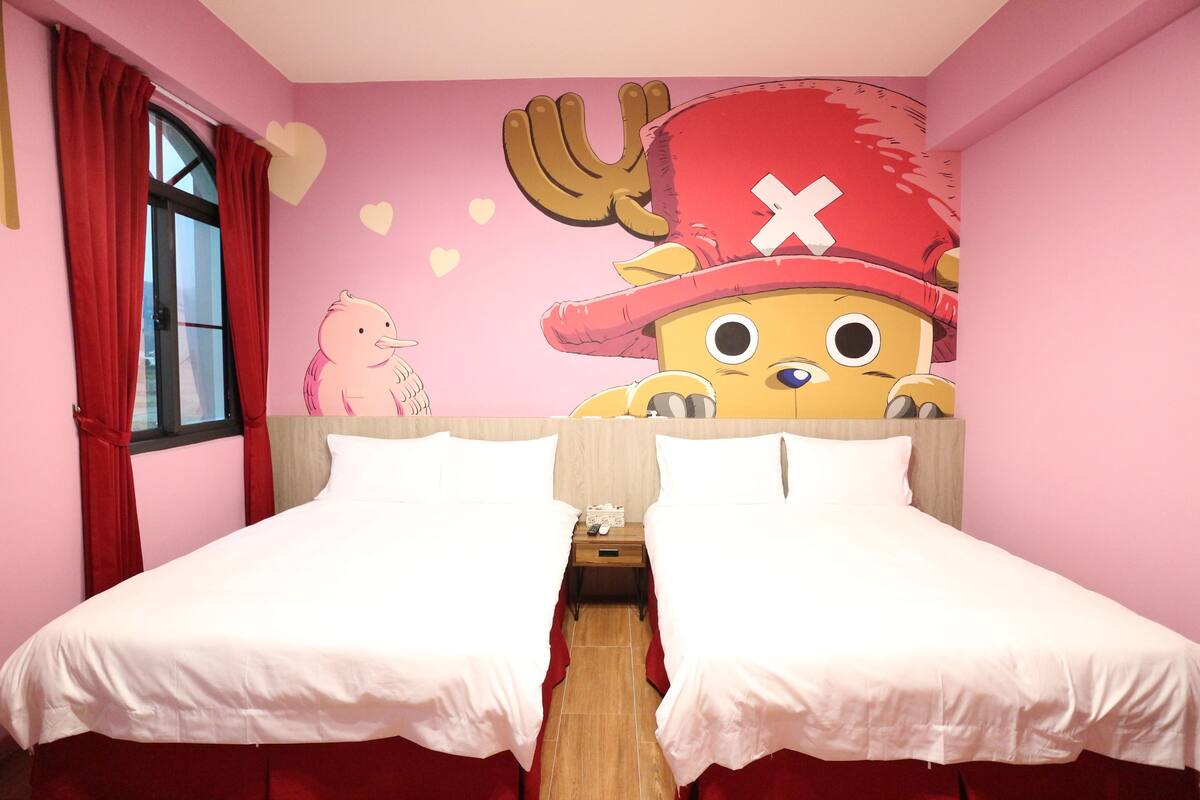 Een kamer met twee bedden, een raam met rode gordijnen en een muurschildering van een cartoonfiguur.