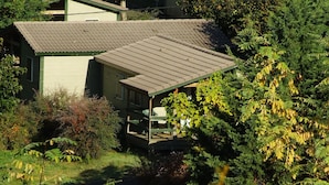 Une maison avec un toit en pente, entourée d’une végétation luxuriante.