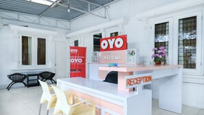 Een receptie met een wit bureau, een bord met de tekst receptie en twee stoelen.