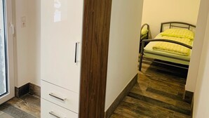 Ein Schlafzimmer mit Bett, Kleiderschrank und einer Tür zu einem weiteren Raum.