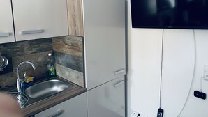 Eine moderne Küche mit Spüle aus Edelstahl, Holzrückwand und einem im Wand eingelassenen Fernseher.