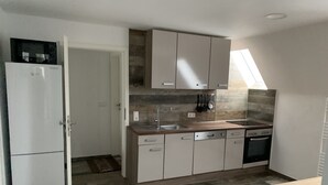 Eine moderne Küche mit Einbauofen, Mikrowelle und Spüle. Ein Fenster sorgt für natürliches Licht, und eine Tür führt in einen anderen Raum.