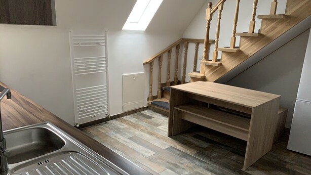Eine Küche mit Holzausziehtisch, Spüle, eingebauter Bank und einer Treppe mit Holzbalken.