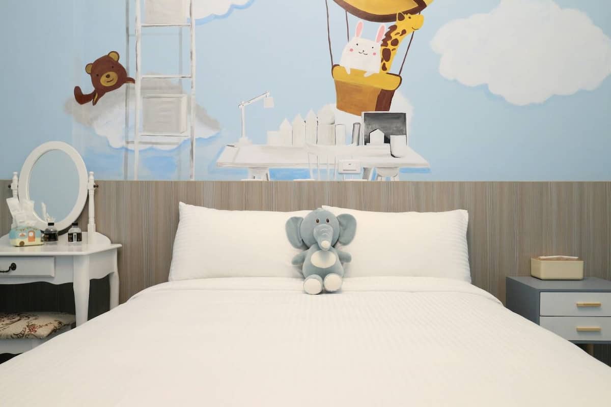 A bedroom with a bed, a nightstand, a dresser, and a wall mural.