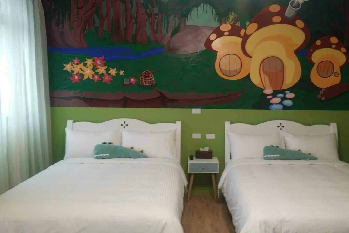 A room with two beds, green walls, and a mural of mushrooms and a forest.