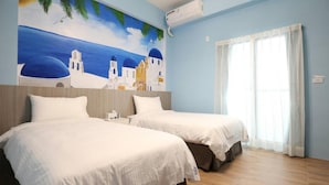 Ein Hotelzimmer mit zwei Betten, einem Wandbild einer Küstenlandschaft und einem großen Fenster mit Vorhängen.