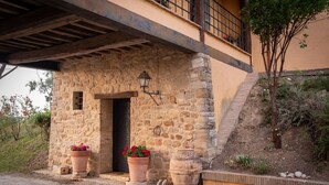 A stone building with a wooden door, potted plants, and a lantern. - Agriturismo Le Cerque (Collazzone)