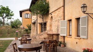 An outdoor patio with wooden tables and chairs, a stone staircase, and potted plants. - Agriturismo Le Cerque (Collazzone)