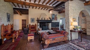 A traditional room with exposed wooden beams, stone walls, and a fireplace. There are wooden furniture pieces and a television. - Agriturismo Le Cerque (Collazzone)