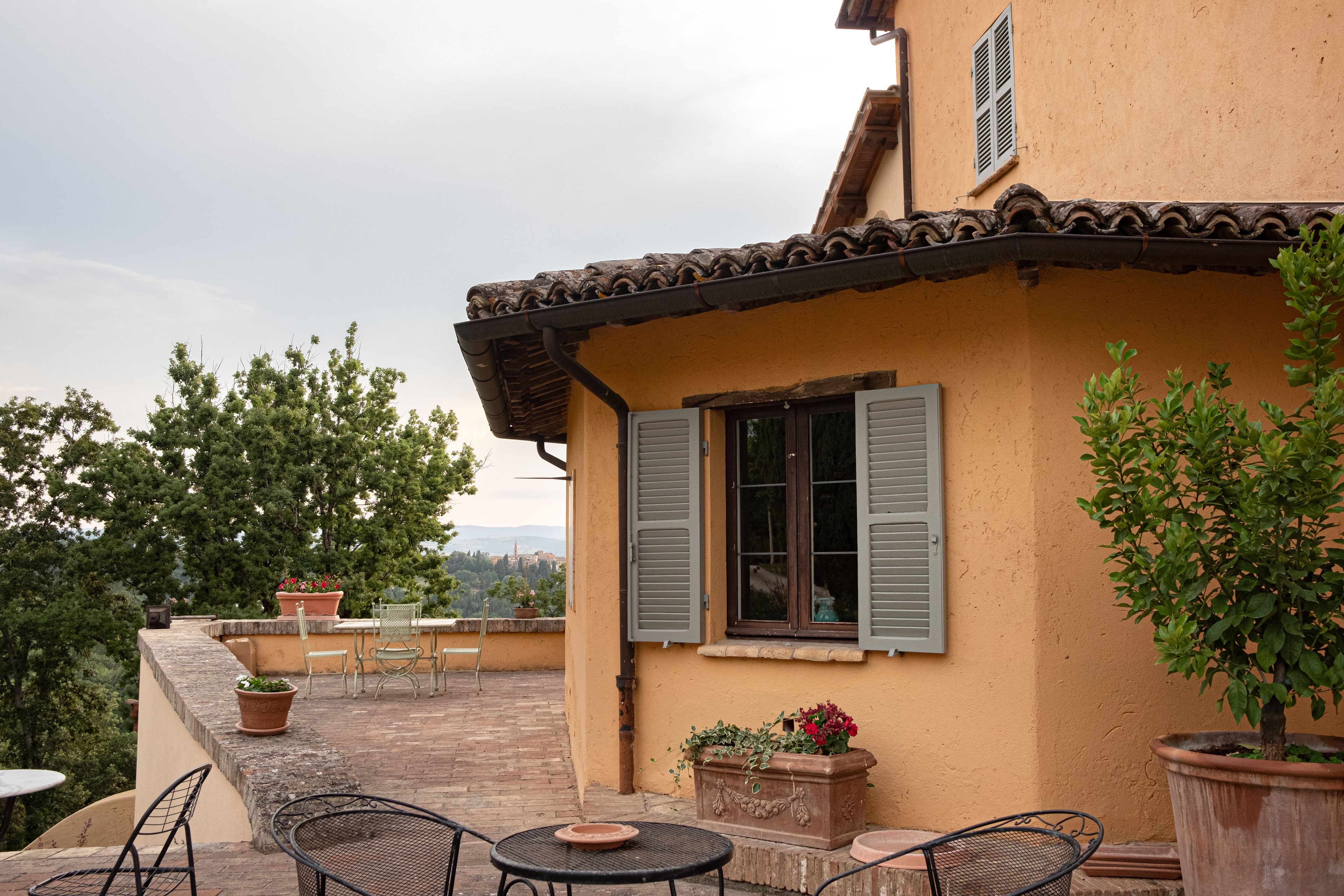 Une terrasse aménagée avec du mobilier d’extérieur, des plantes en pot et une vue sur la campagne.