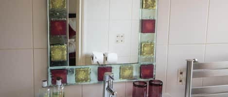 A bathroom with a white sink, a mirror with a decorative frame, and a towel rack.