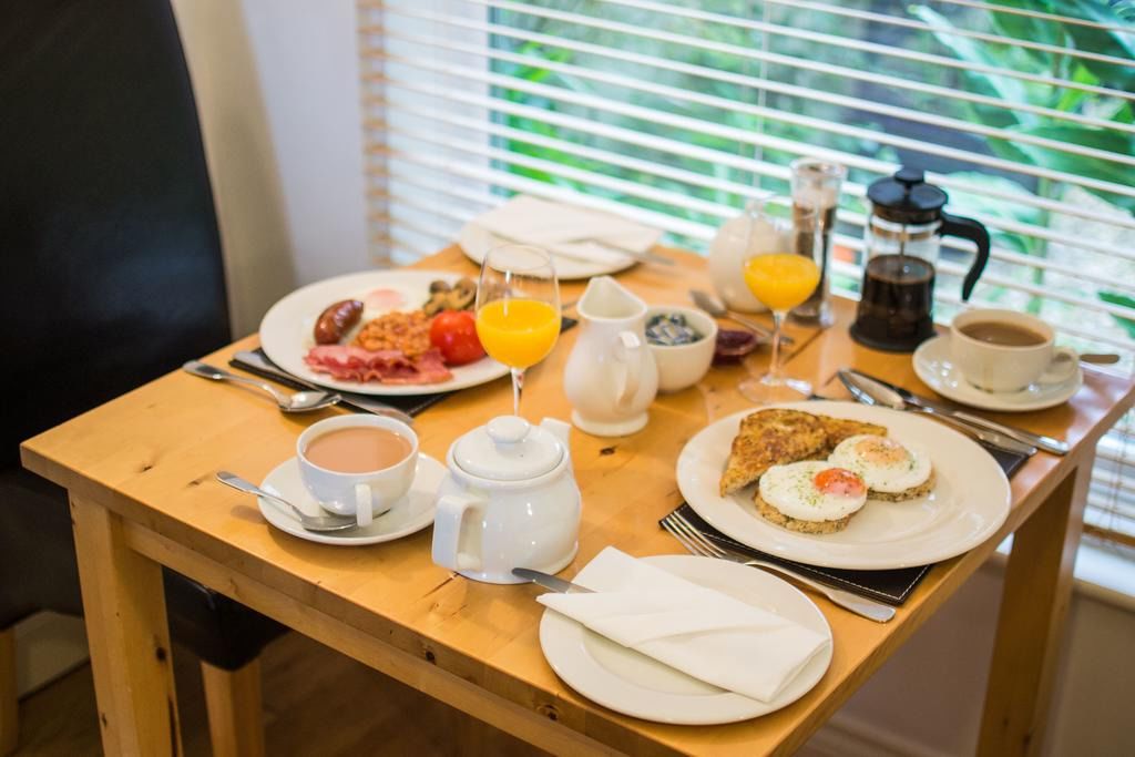 Une table de petit-déjeuner avec des assiettes remplies de nourriture, du café et du jus de fruits.