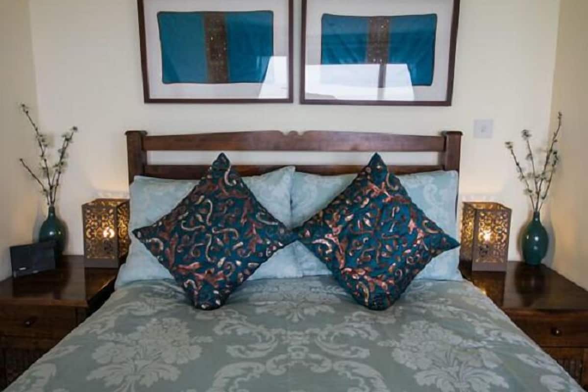 A bedroom with a large bed, two framed pictures above the headboard, and two bedside tables with lamps.