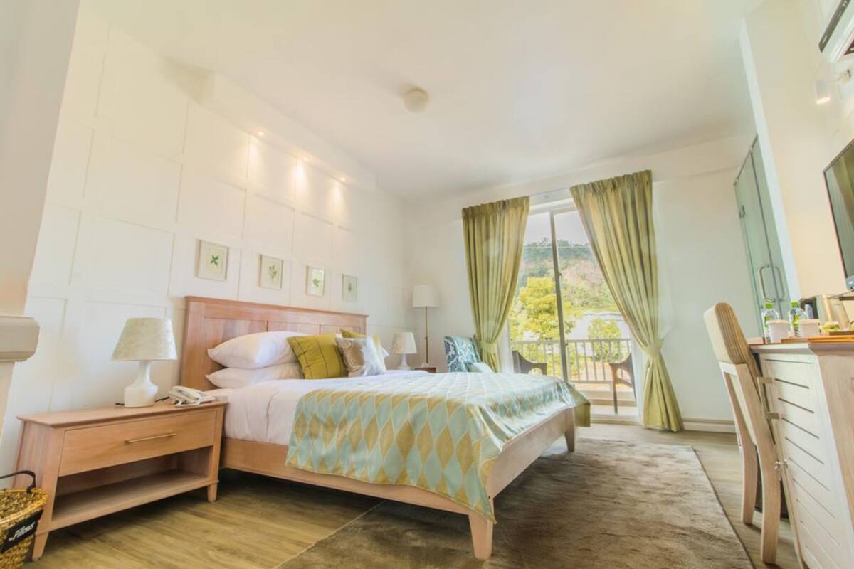 Une chambre d’hôtel avec un lit, une table de chevet, une lampe et une vue sur l’extérieur.
