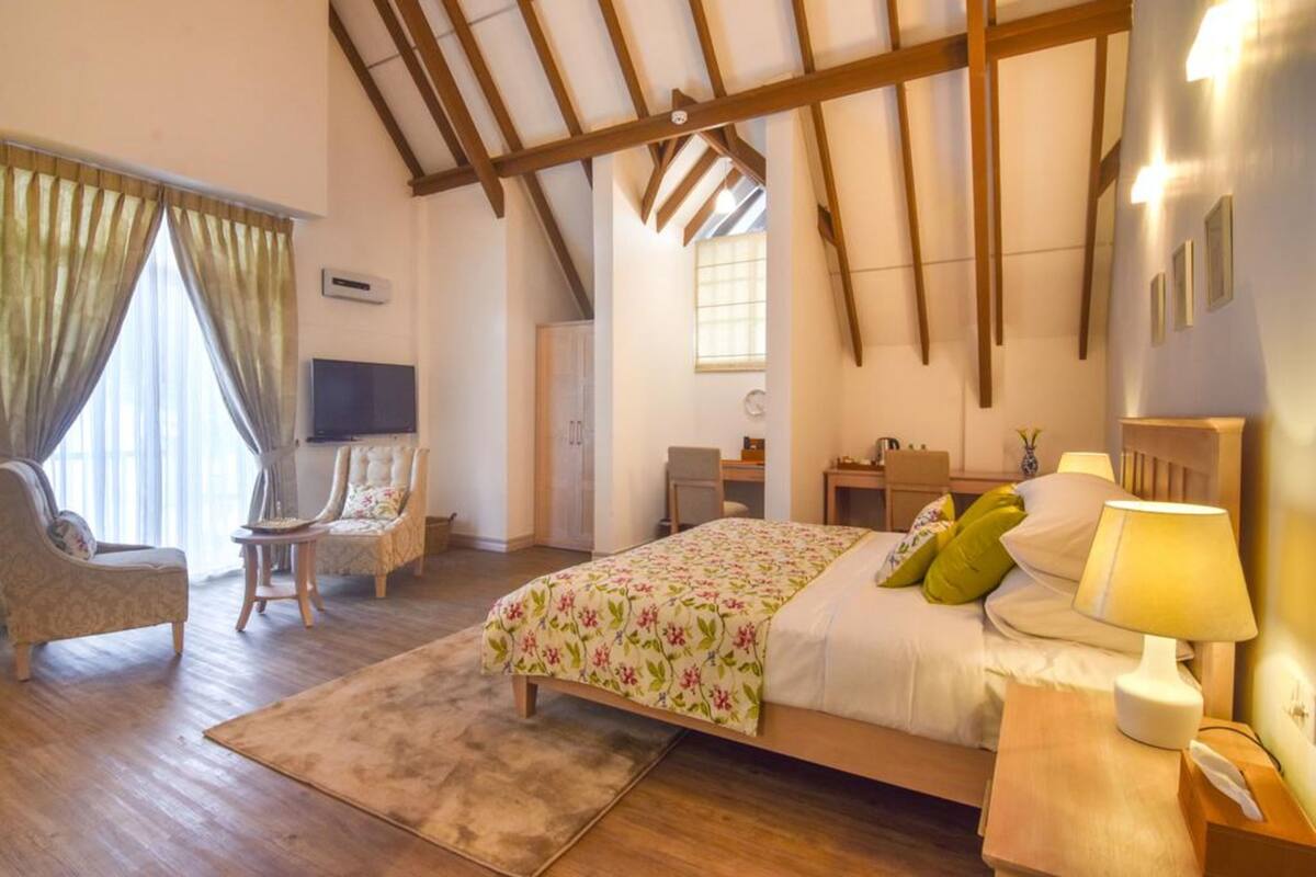 Une chambre à coucher avec un lit, un bureau, une chaise, une télévision et une fenêtre.