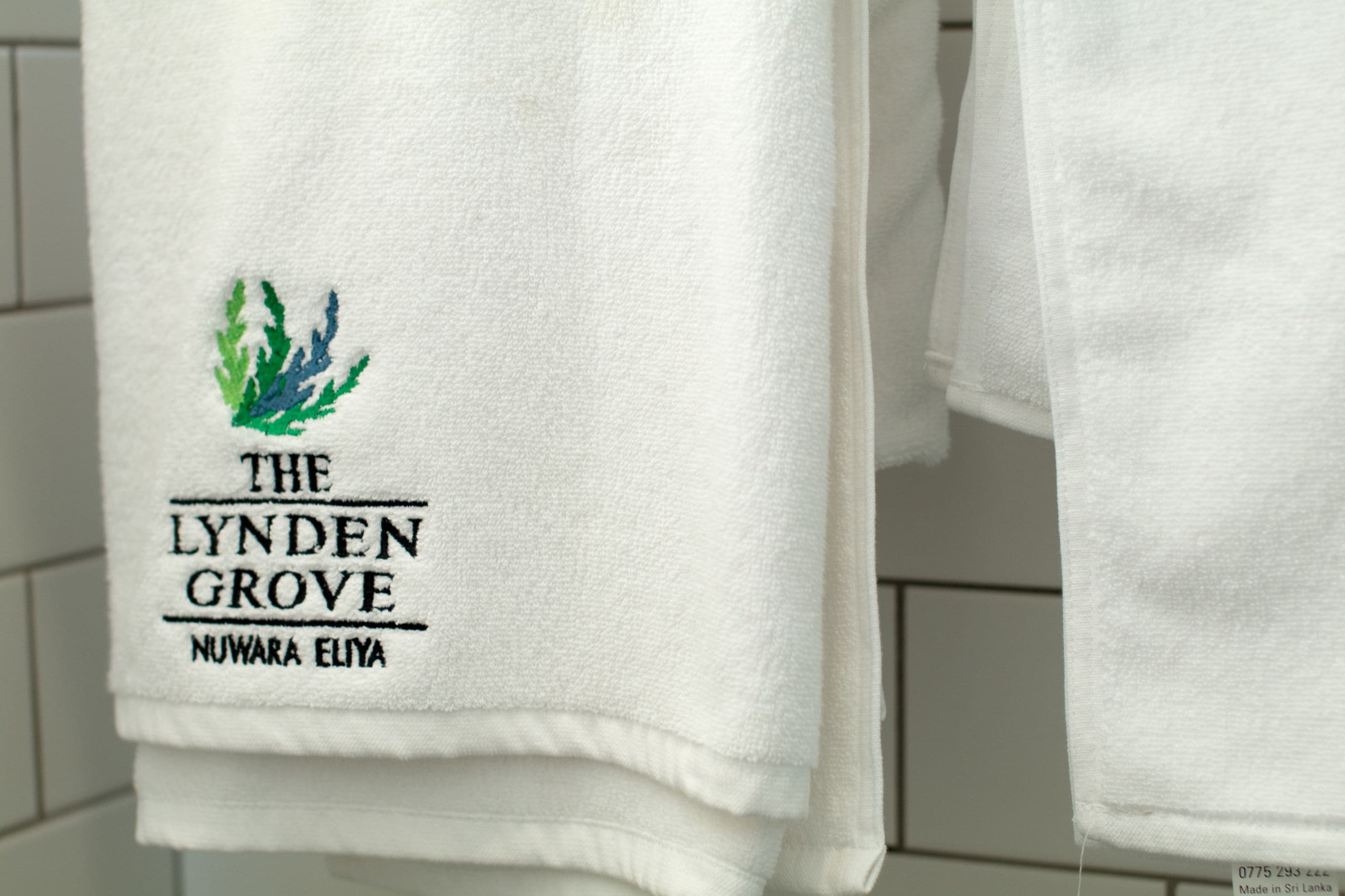 Toalla blanca con texto y logo bordados, que sugiere un entorno de hotel o spa.