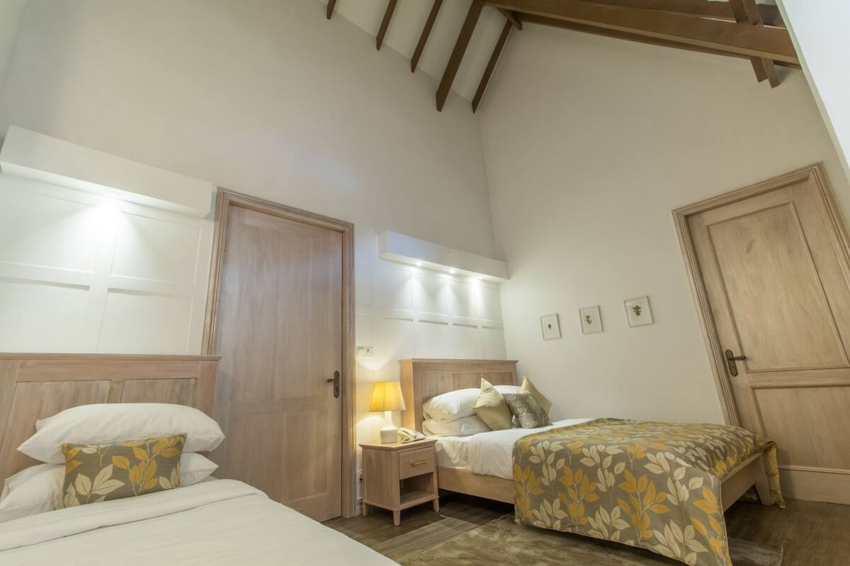 Une chambre avec deux lits, une table de chevet, une lampe et un ventilateur de plafond.