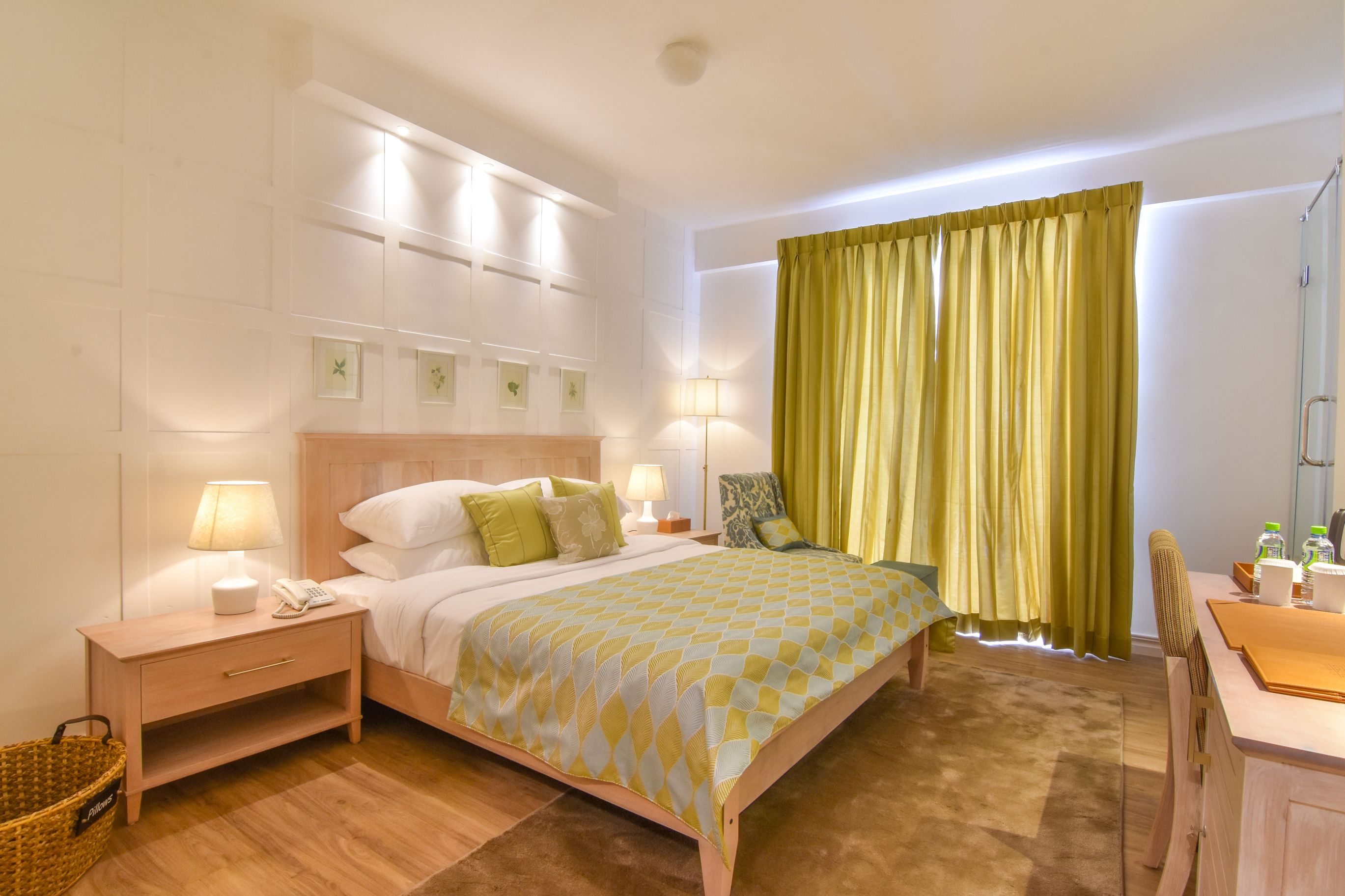 A hotel room with a bed, bedside lamps, a desk, and a chair.