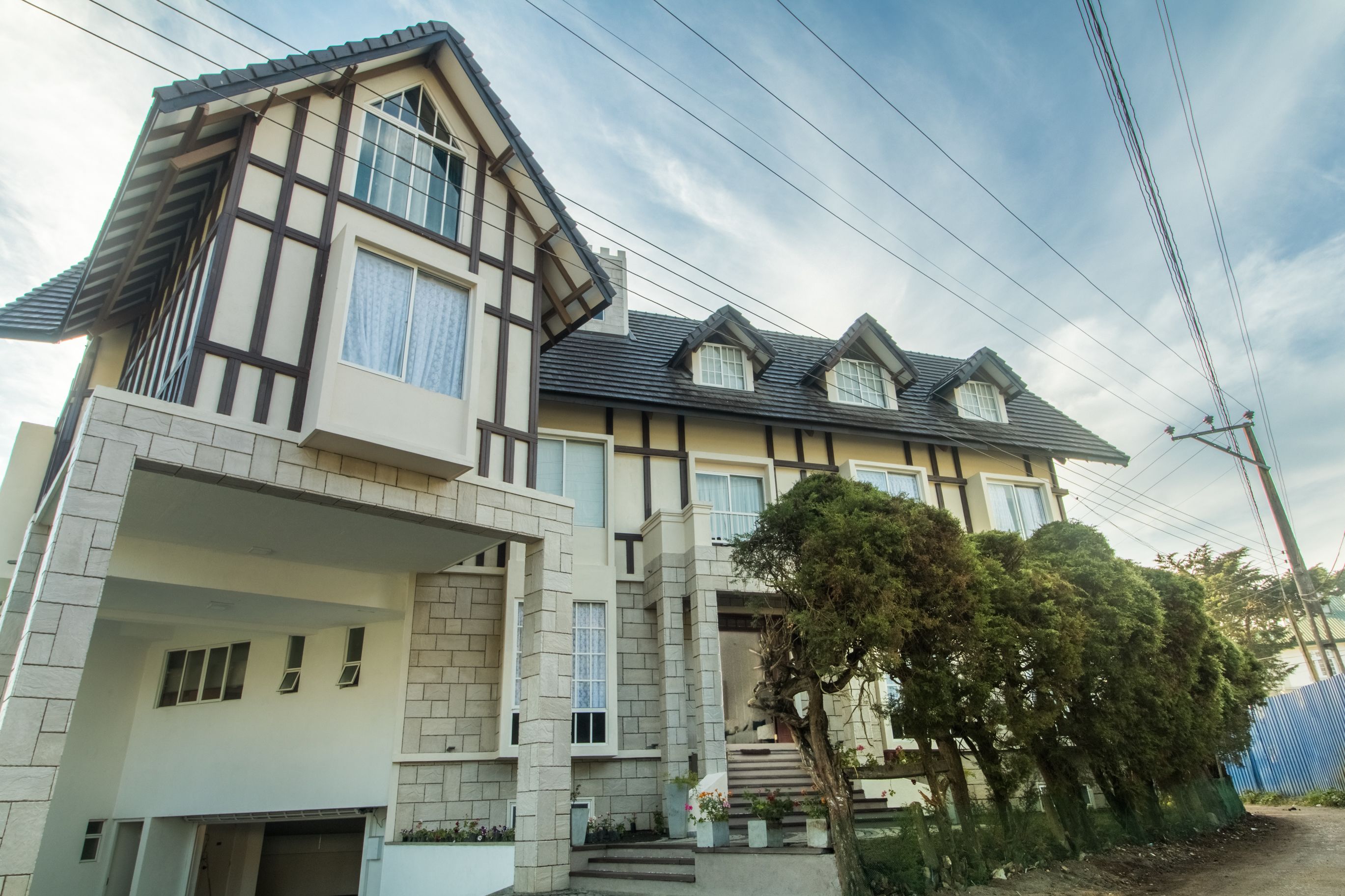 A two-story house with a steeply pitched roof, multiple windows, and a front porch.