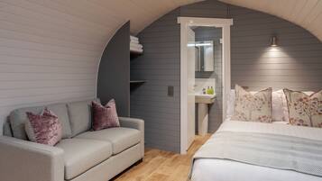 Un dormitorio con cama, sofá, un baño pequeño y un techo curvo.