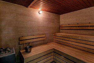 Una sauna con bancos de madera, un balde y una lámpara en el techo.