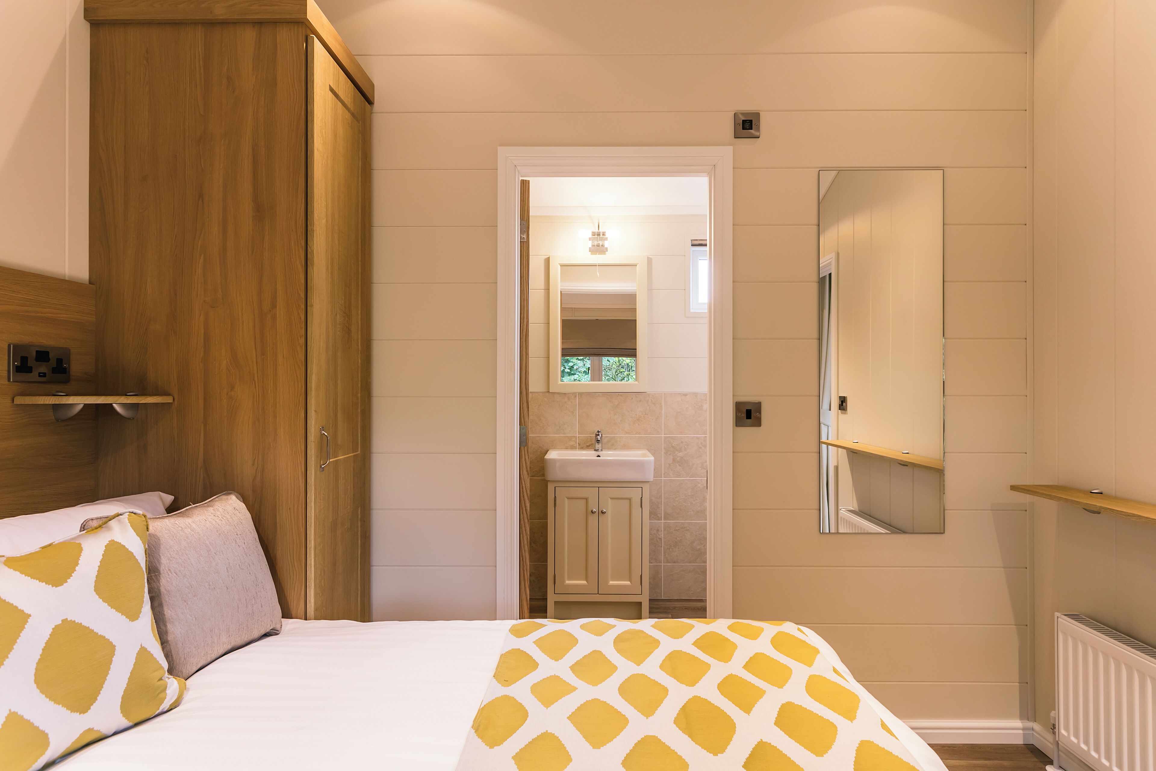Un dormitorio con cama, armario de madera, baño con lavamanos y espejo.
