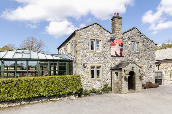 A stone building with a green roof, a small entrance, and a poster on the wall.