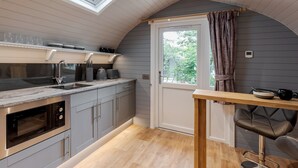 Cocina compacta con horno integrado, un lavamanos y una ventana sobre la encimera.