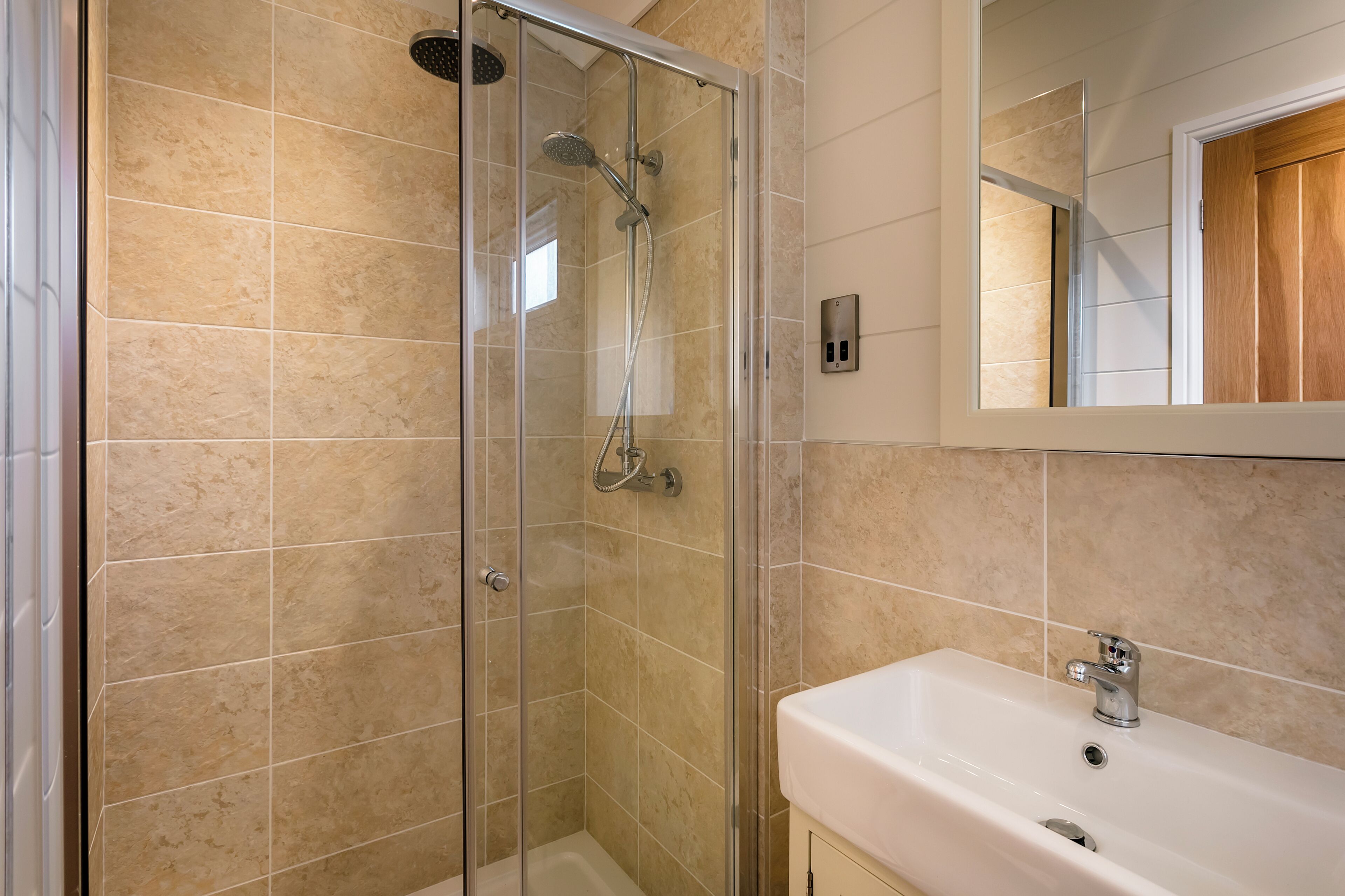 A bathroom with a glass-enclosed shower, a white sink, and a mirror above the sink.