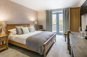 A bedroom with a large bed, bedside tables, a desk with a chair, a TV, and a view of the outdoors.